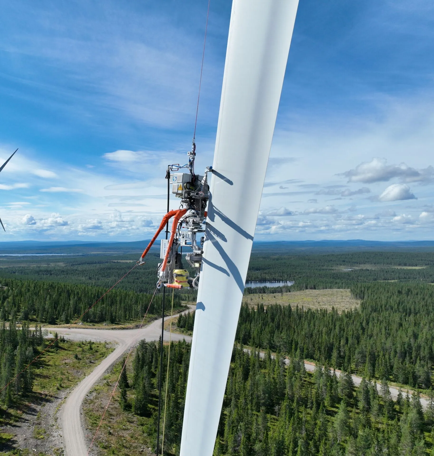 Aerones robot working on a wind turbine blade above a forest